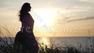 一个年轻的女孩站在海边看着美丽的日落。 4K，3840x2160。 <strong>高清高清</strong>